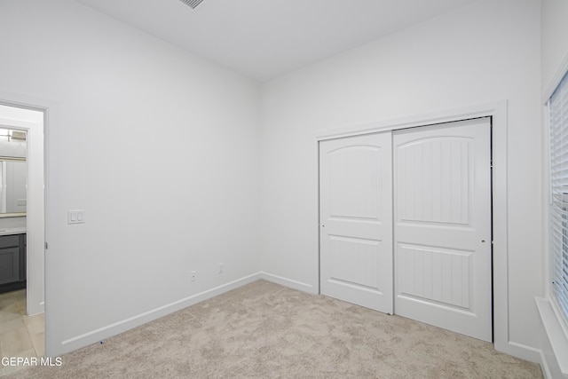 unfurnished bedroom with light carpet and a closet