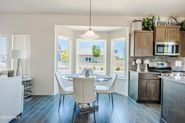 kitchen featuring light stone counters, decorative light fixtures, appliances with stainless steel finishes, and dark wood-type flooring