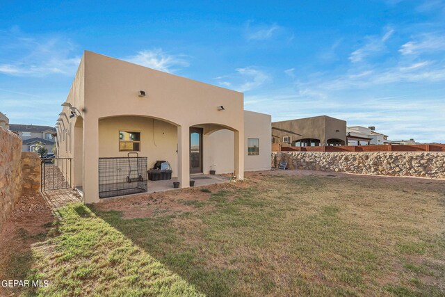 back of property featuring a lawn and a patio area