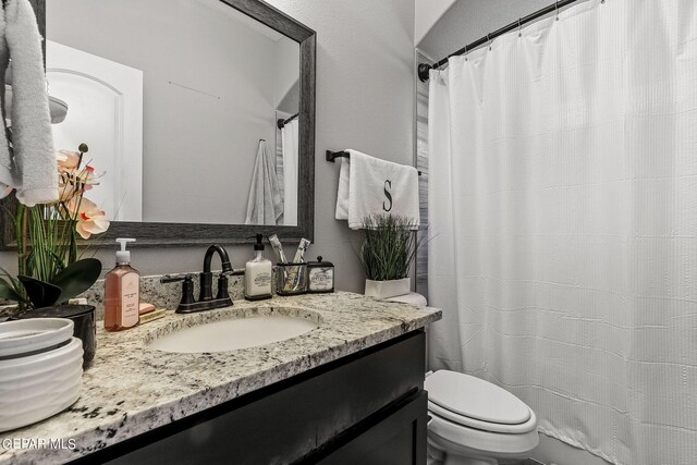 bathroom featuring a shower with curtain, vanity, and toilet