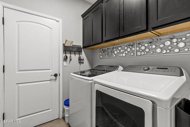 laundry room with washer and clothes dryer, hardwood / wood-style floors, and cabinets