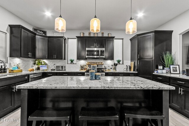 kitchen with appliances with stainless steel finishes, light wood-type flooring, and a kitchen island