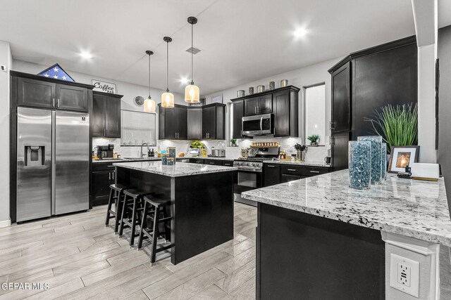 kitchen with tasteful backsplash, a kitchen island, a breakfast bar area, stainless steel appliances, and decorative light fixtures