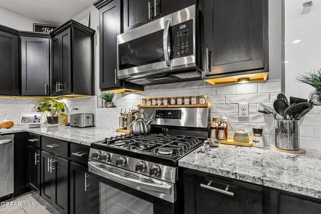 kitchen featuring decorative backsplash, stainless steel appliances, and light stone countertops