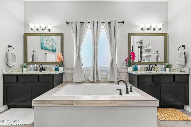 bathroom with hardwood / wood-style floors, tiled bath, and vanity