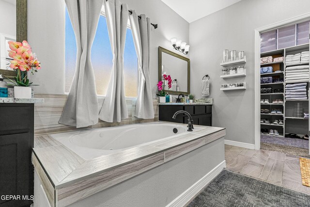 bathroom featuring vanity and tiled bath