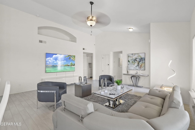 living room with ceiling fan, light hardwood / wood-style floors, and high vaulted ceiling