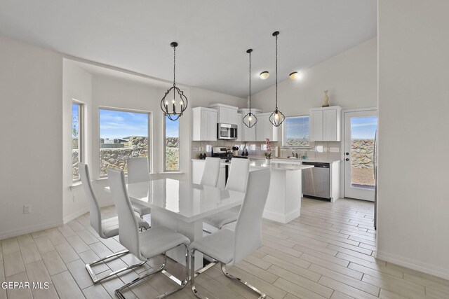 dining area with a notable chandelier, light hardwood / wood-style floors, and a high ceiling