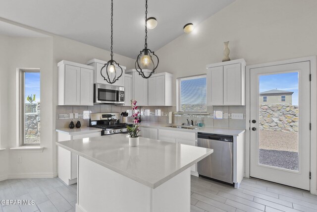 kitchen with decorative light fixtures, a center island, stainless steel appliances, and white cabinets