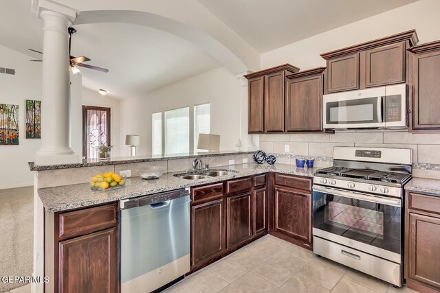 kitchen featuring kitchen peninsula, stainless steel appliances, light stone countertops, ceiling fan, and ornate columns