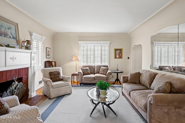 living room with a healthy amount of sunlight, carpet flooring, crown molding, and a brick fireplace