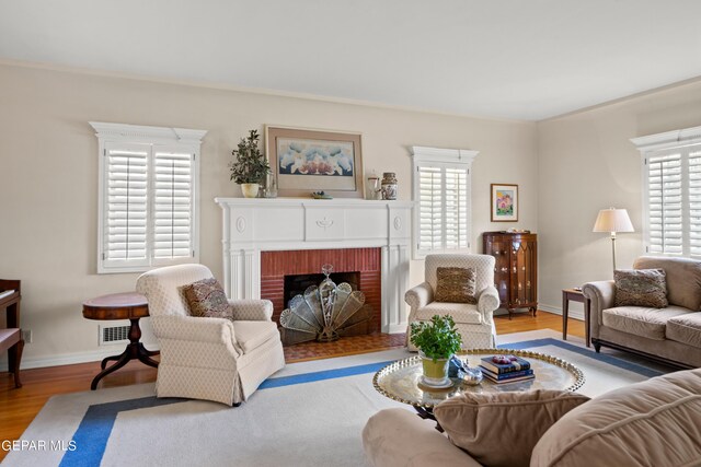 living room with ornamental molding, a brick fireplace, light hardwood / wood-style floors, and plenty of natural light