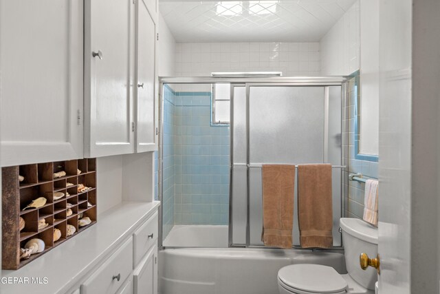 full bathroom with bath / shower combo with glass door, tasteful backsplash, vanity, and toilet