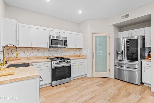 kitchen featuring light hardwood / wood-style floors, white cabinetry, backsplash, stainless steel appliances, and sink