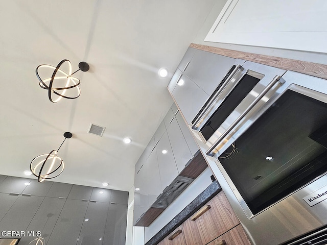 interior space featuring white cabinets, pendant lighting, and an inviting chandelier