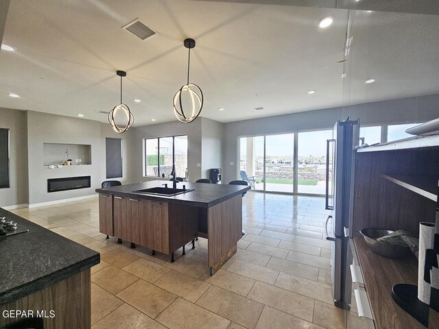 kitchen with decorative light fixtures and a center island with sink