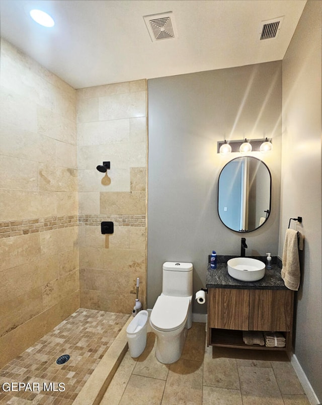 bathroom featuring vanity, toilet, and tiled shower