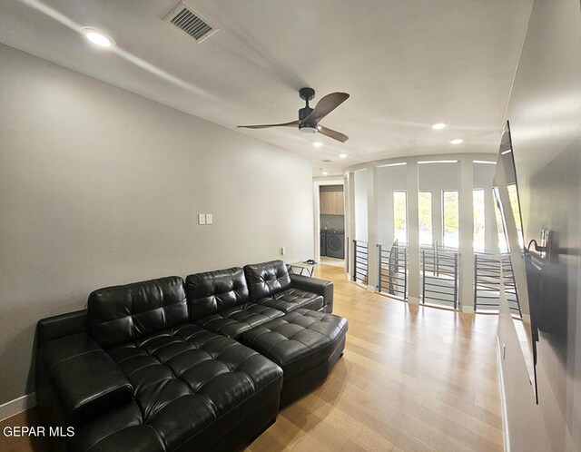 living room with ceiling fan, light hardwood / wood-style floors, and washer / dryer