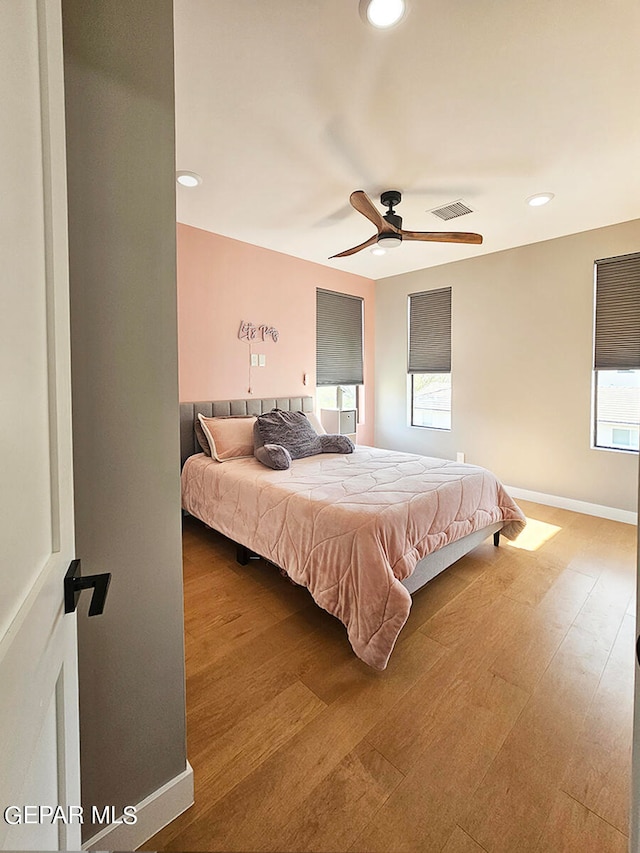 bedroom with multiple windows, wood-type flooring, and ceiling fan