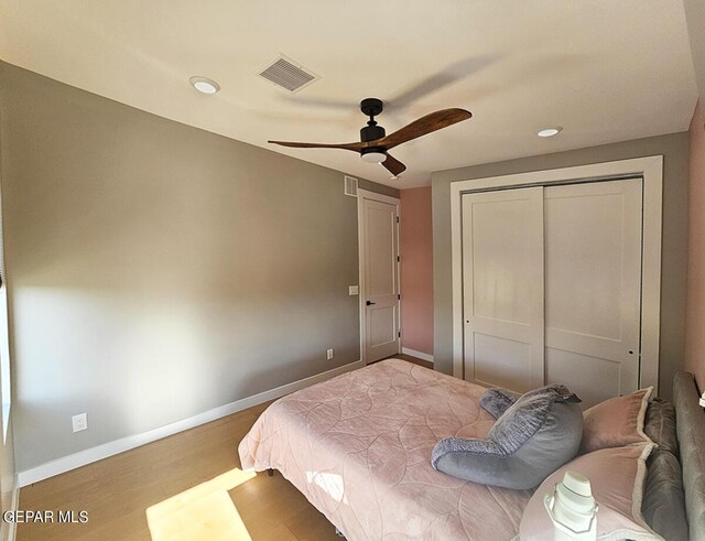 bedroom featuring hardwood / wood-style flooring, ceiling fan, and a closet