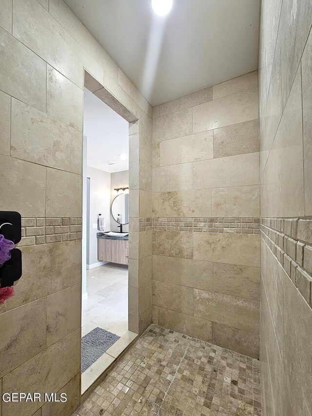 bathroom with a tile shower and vanity