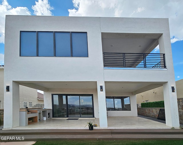 back of house featuring a patio area, a balcony, and exterior kitchen