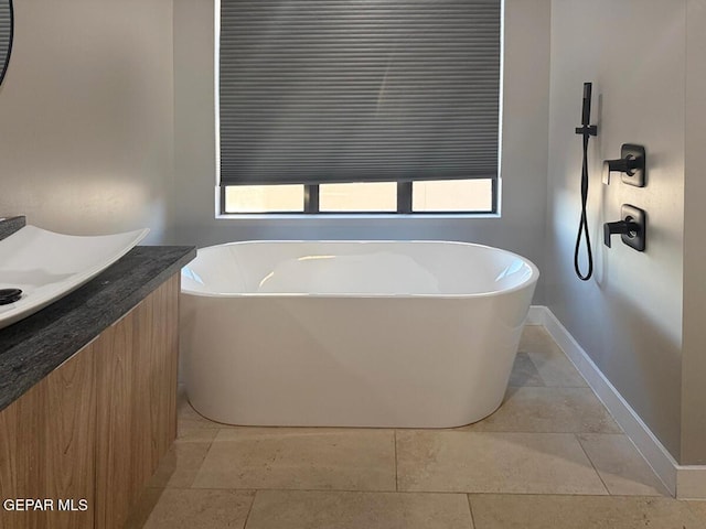 bathroom with tile patterned flooring, a healthy amount of sunlight, vanity, and a bathing tub