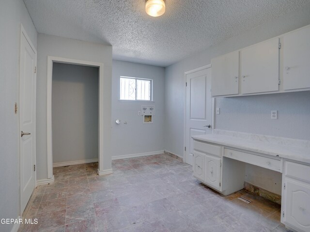 unfurnished office featuring built in desk and a textured ceiling