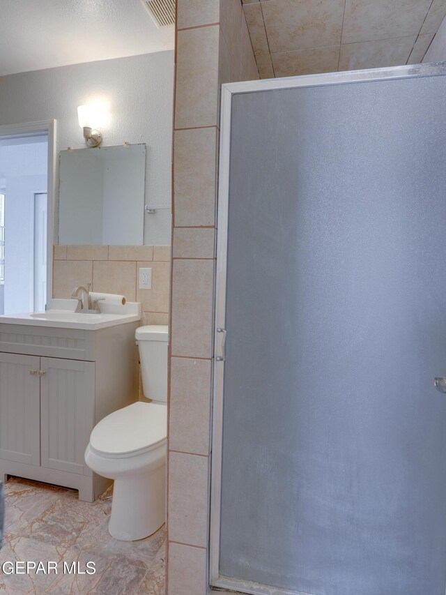 bathroom featuring tile walls, vanity, walk in shower, toilet, and tile patterned floors