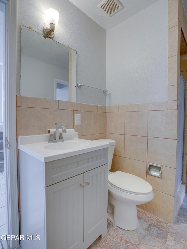 bathroom featuring tile walls, tile patterned flooring, vanity, and toilet