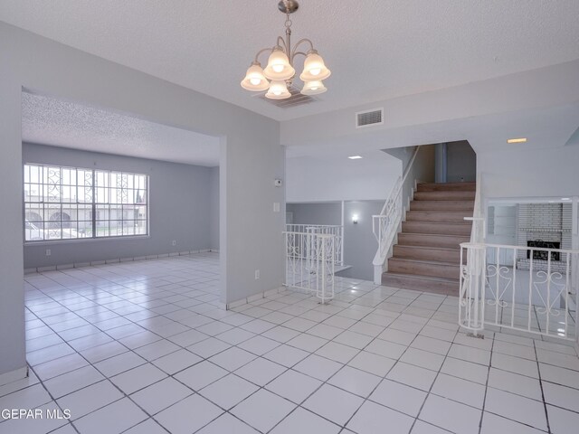 tiled spare room with an inviting chandelier and a textured ceiling