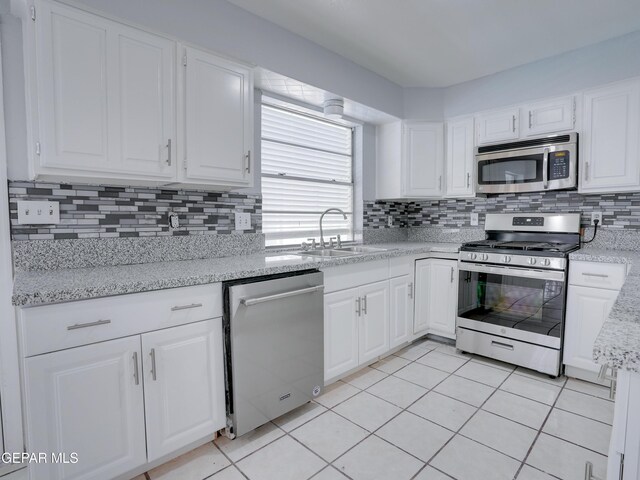 kitchen featuring appliances with stainless steel finishes, decorative backsplash, white cabinetry, and sink