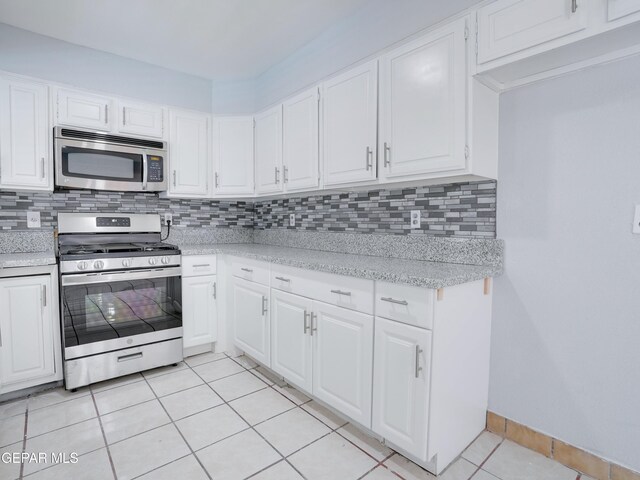 kitchen with white cabinetry, backsplash, appliances with stainless steel finishes, light tile patterned floors, and light stone countertops