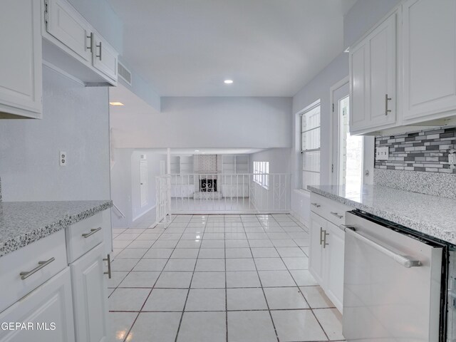 kitchen with white cabinetry, light stone counters, light tile patterned flooring, and stainless steel dishwasher