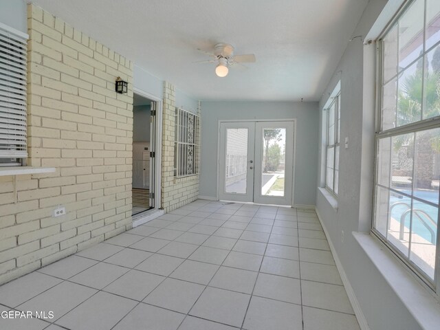 unfurnished sunroom with a wealth of natural light, ceiling fan, and french doors