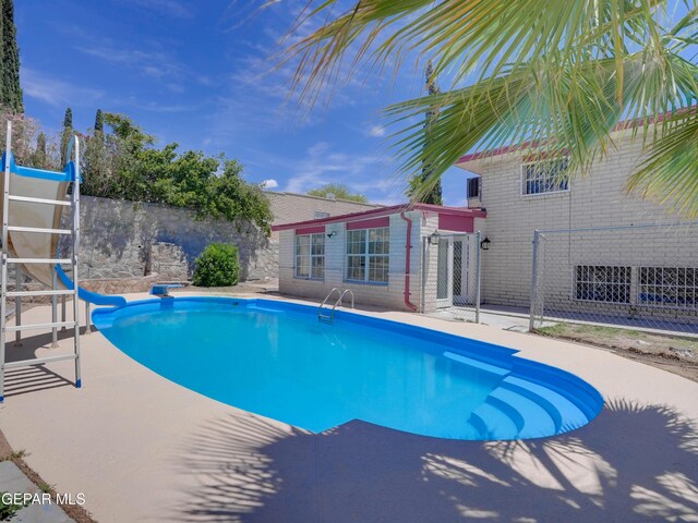 view of swimming pool featuring a water slide and a patio area