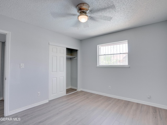 unfurnished bedroom with a closet, light hardwood / wood-style floors, ceiling fan, and a textured ceiling