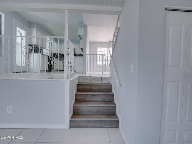 staircase featuring tile patterned flooring, a textured ceiling, and plenty of natural light