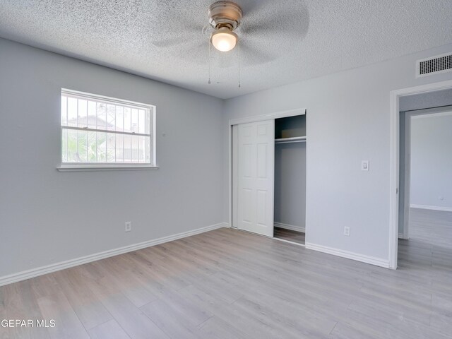 unfurnished bedroom featuring a closet, light hardwood / wood-style floors, ceiling fan, and a textured ceiling