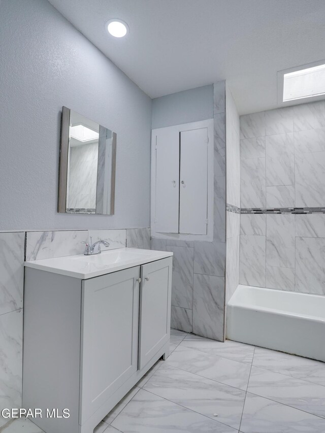 bathroom featuring tile walls, vanity, and a bathing tub