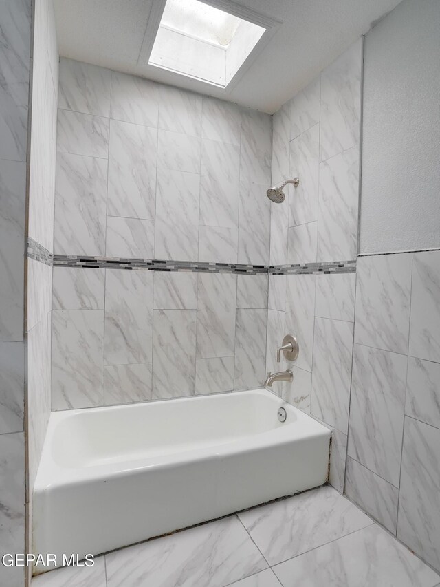 bathroom with a skylight and tiled shower / bath