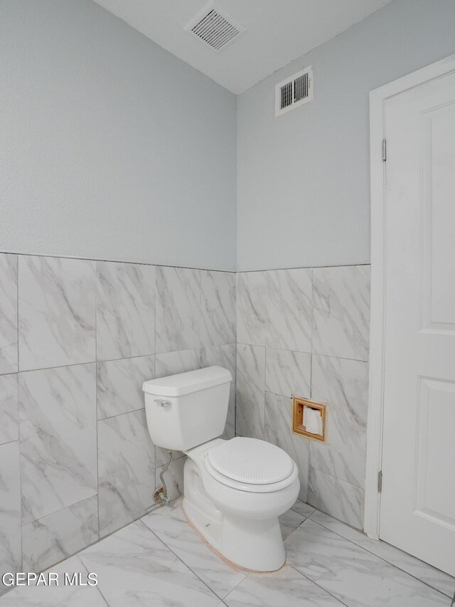 bathroom with tile walls and toilet