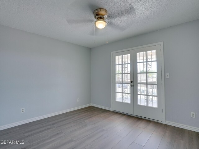 empty room with ceiling fan, hardwood / wood-style flooring, french doors, and a textured ceiling