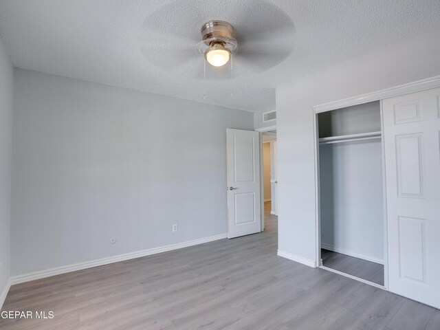 unfurnished bedroom with ceiling fan, a textured ceiling, light hardwood / wood-style flooring, and a closet