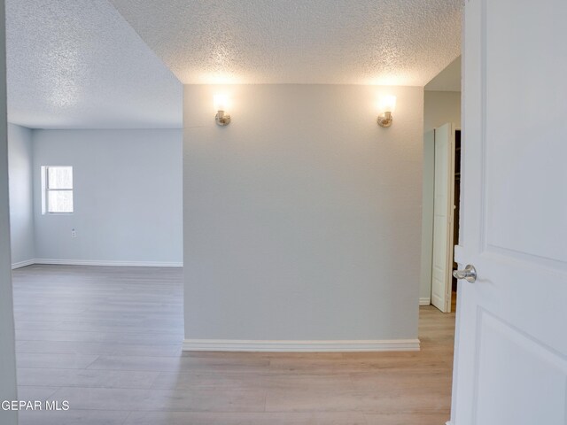 empty room featuring light wood-type flooring and a textured ceiling