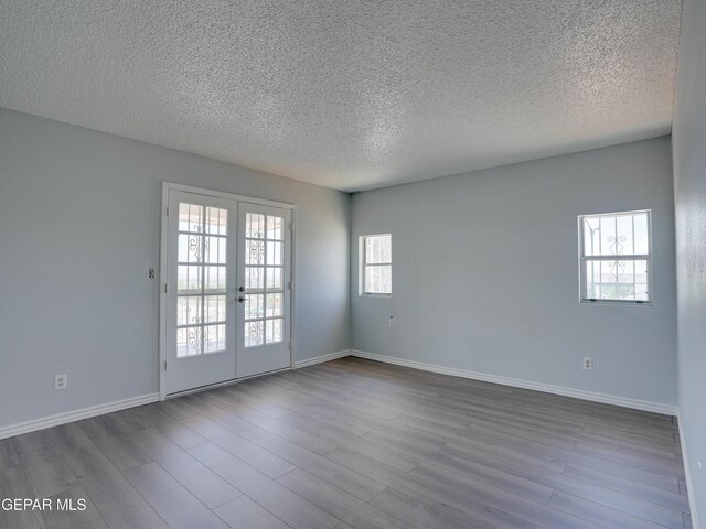 spare room with light wood-type flooring, a textured ceiling, and french doors