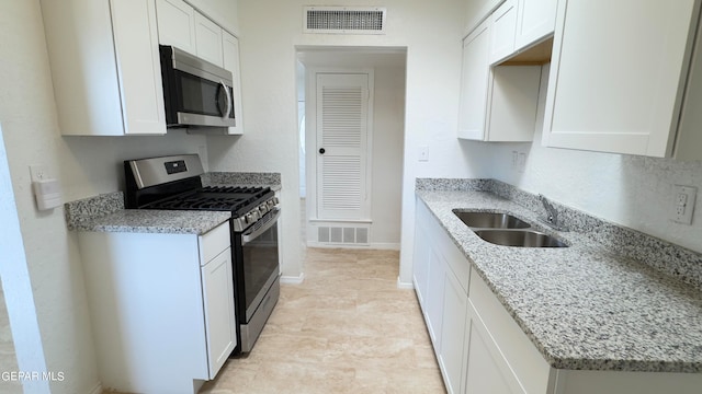 kitchen featuring light stone counters, white cabinetry, sink, and appliances with stainless steel finishes