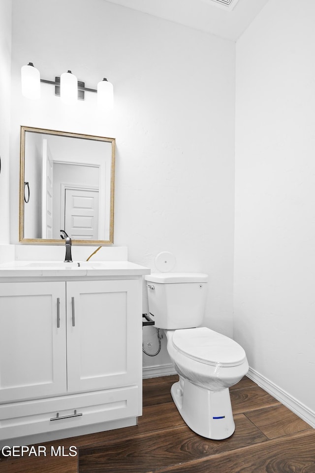 bathroom with vanity, toilet, and hardwood / wood-style floors