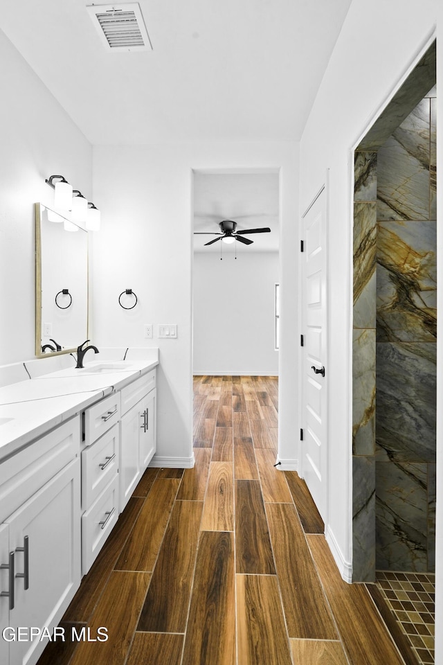 bathroom with ceiling fan, vanity, and a tile shower