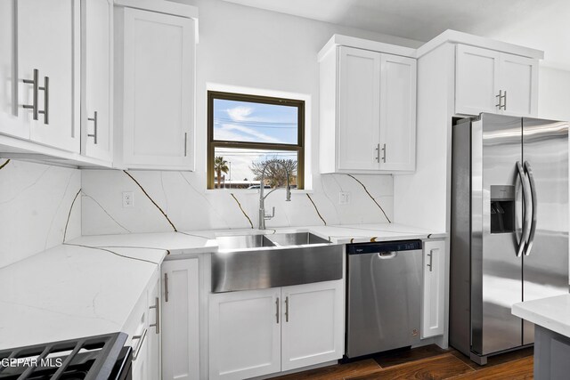 kitchen featuring sink, appliances with stainless steel finishes, white cabinetry, light stone counters, and tasteful backsplash